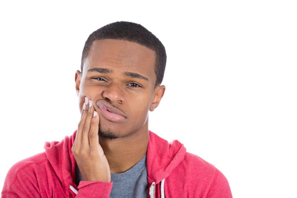 Patient holding face in pain due to dental emergency near 27103