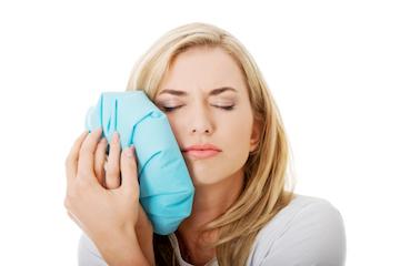 Woman Icing Side of Face in need of a Tooth Extraction in Winston-Salem