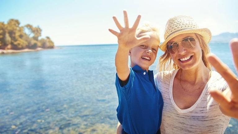 mother and young son waving by an ocean