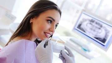 woman with a tooth shade chart in dental office