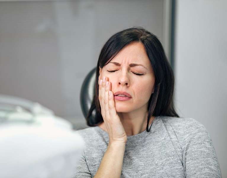 woman in pain holding her left cheek