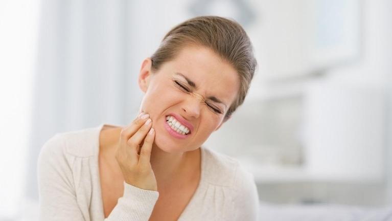 woman holding her jaw in pain